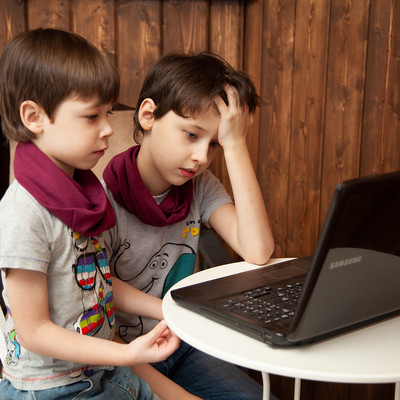zwei Jungs nachdenklich vor offenem Laptop